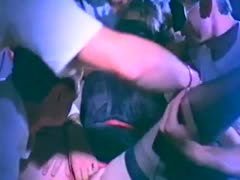 A horny brunette slut wearing a mask gets fucked by many guys in a gang.